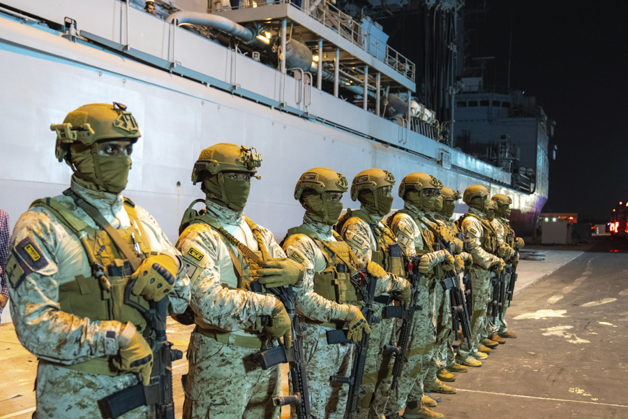 In this photo provided by Saudi Ministry of Media, commandos from the Saudi Royal Naval Forces, line up in front of a ship carrying evacuees at Jeddah Port, Saudi Arabia, Monday, April 24, 2023, after being evacuated from Sudan to escape the conflict.