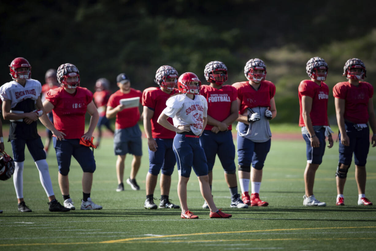 FILE - Simon Fraser University football team kicker Kristie Elliott, center, stands on the field with teammates during practice in Burnaby, British Columbia, Tuesday, Sept. 21, 2021. The only Canadian college with NCAA membership is shutting down its football program. Simon Fraser President Joy Johnson announced the decision in a letter Tuesday, April 4, 2023 saying that uncertainties about the future for the program led to the decision to discontinue it.