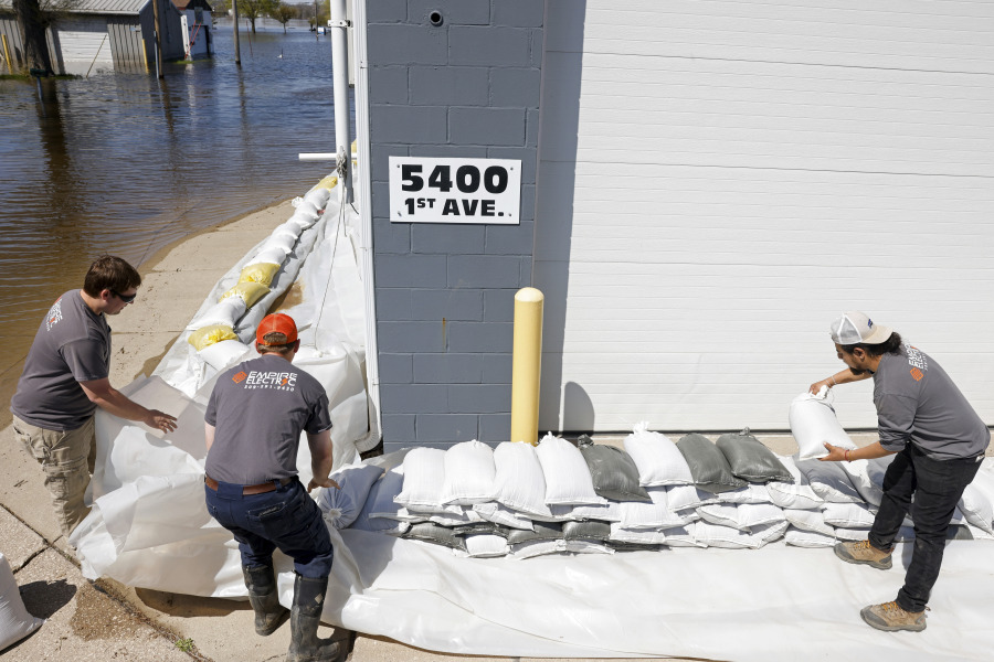 Empire Electric employees place sandbags around the front of the business as the Mississippi River continues to rise on Wednesday in Moline, Ill.