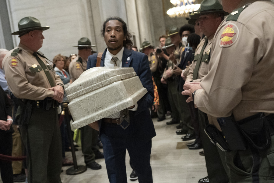 Rep. Justin Jones, D-Nashville, carries a casket past Tennessee State Troopers as he walks to the House chambers to demonstrate the need for gun reform laws at the state Capitol Monday, April 17, 2023 in Nashville, Tenn.