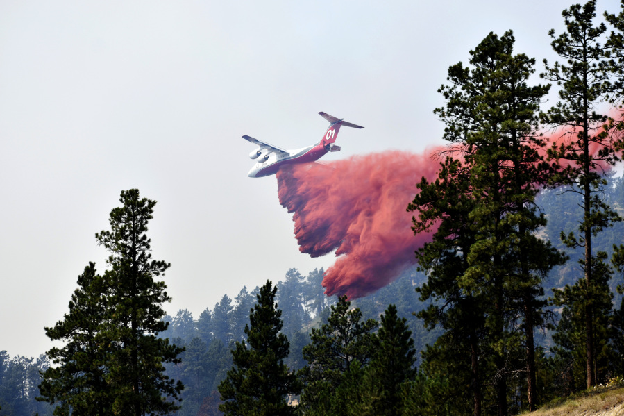 FILE - An aircraft drops fire retardant to slow the spread of the Richard Spring fire, east of Lame Deer, Mont., on Aug. 11, 2021. A legal dispute in Montana could drastically curb the government's use of aerial fire retardant to combat wildfires. Environmentalists have sued the U.S. Forest Service over waterways being polluted with the potentially toxic red slurry that's dropped from aircraft. Forest Service officials have acknowledged more than 200 cases of retardant landing in water.