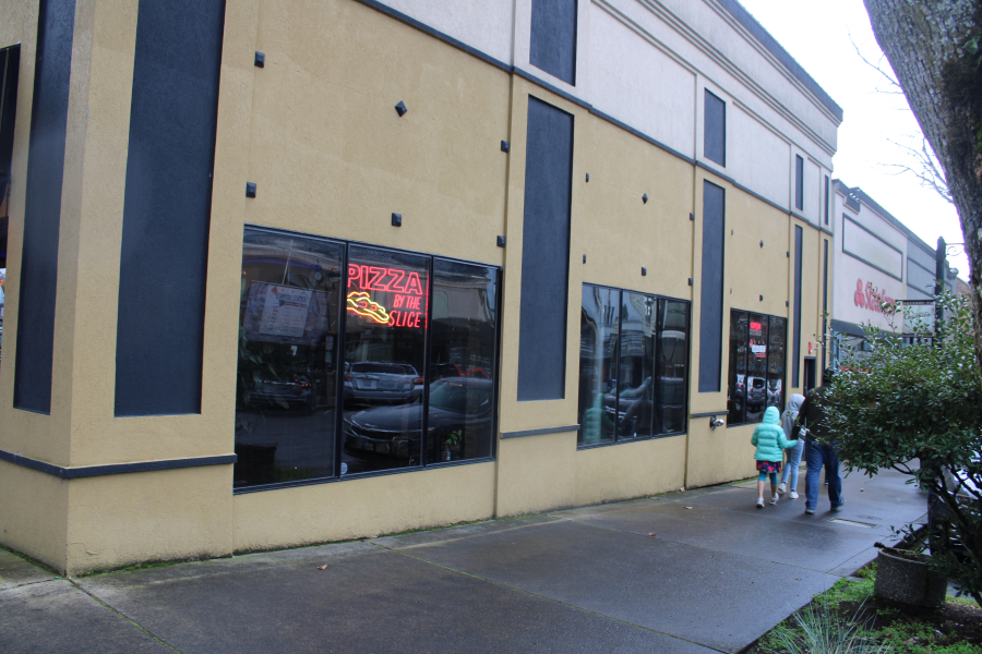 Kelly Moyer/Post-Record files 
 A family passes by Camas Slices in downtown Camas on April 10, 2021. A holding company affiliated with the nearby Journey Community Church recently purchased the former Camas Slices building on the corner of Northeast Cedar Street and Northeast Fourth Avenue in downtown Camas, as well as the adjacent building that once housed a State Farm insurance office. Church leaders say they plan to host community focus groups this spring to help gather ideas about how it might turn the former pizza shop into a youth-centered space.