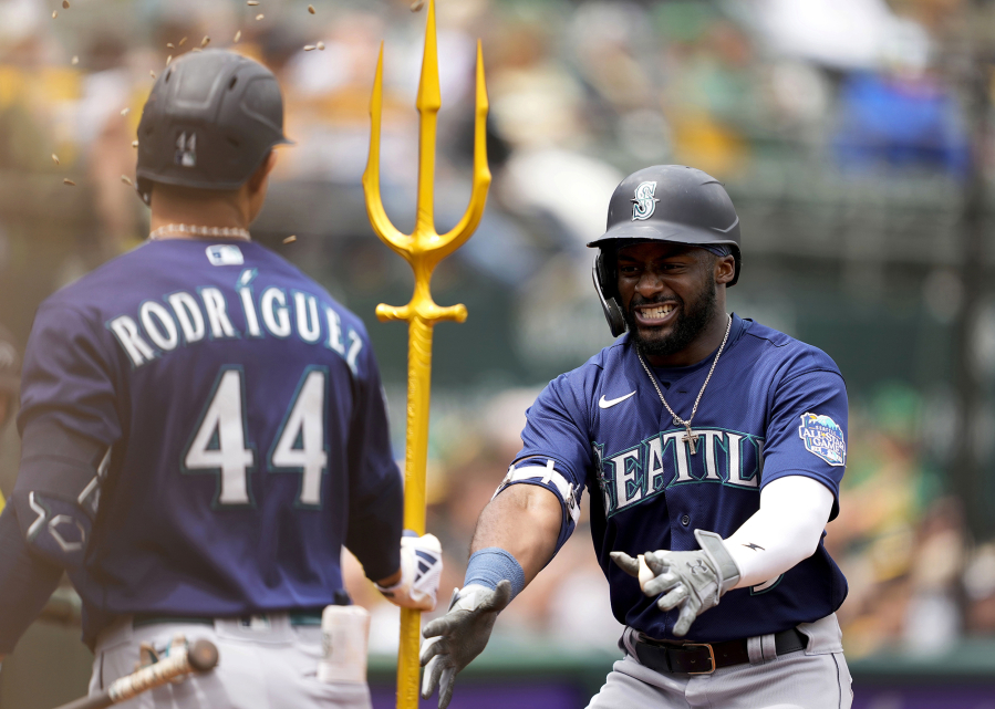 Seattle Mariners' Taylor Trammell, right, celebrates with teammate Julio Rodriguez (44) in the dugout after hitting a two-run home run against the Oakland Athletics during the third inning of a baseball game in Oakland, Calif., Thursday, May 4, 2023.