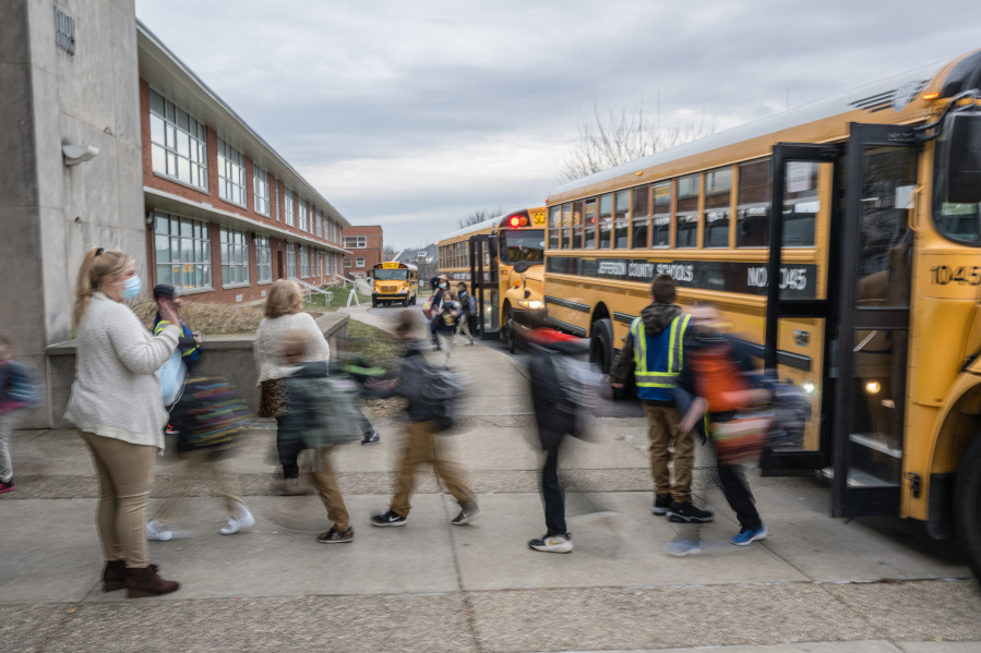 A teacher waves to her students as they get off the bus at Carter Traditional Elementary School on Jan. 24, 2022, in Louisville, Kentucky.