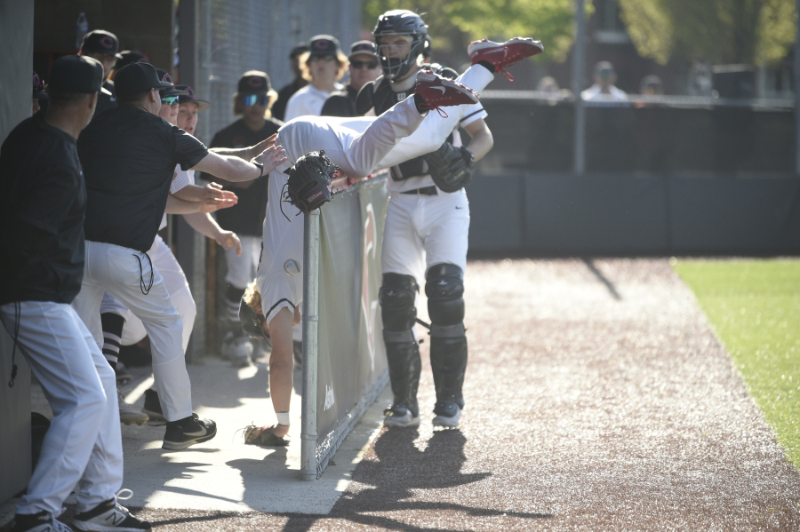 Camas first baseman Boston Jensen falls over the railing of the Camas dugout while chasing a foul ball during a bi-district first-round game against Sumner on May 9, 2023 at Camas High School.