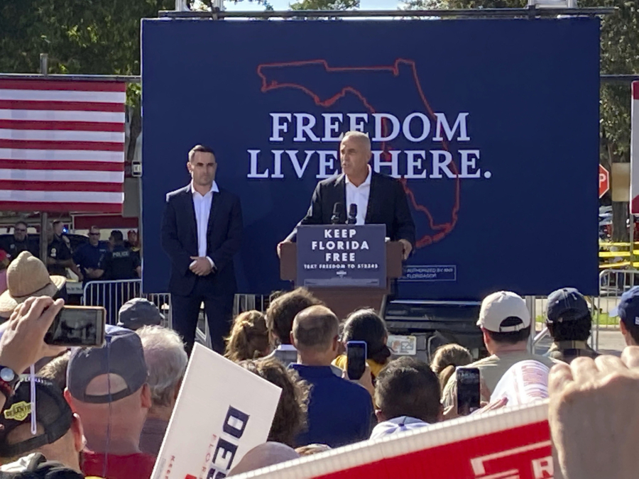 Andrew Pollack, whose daughter Meadow was killed in the Marjory Stoneman Douglas High School massacre, at the lectern speaking on behalf of Florida Gov. Ron DeSantis at a campaign rally in Coral Springs on Sunday, Oct. 16, 2022. Hunter Pollack, left, who was Meadow's brother, also spoke at the event.