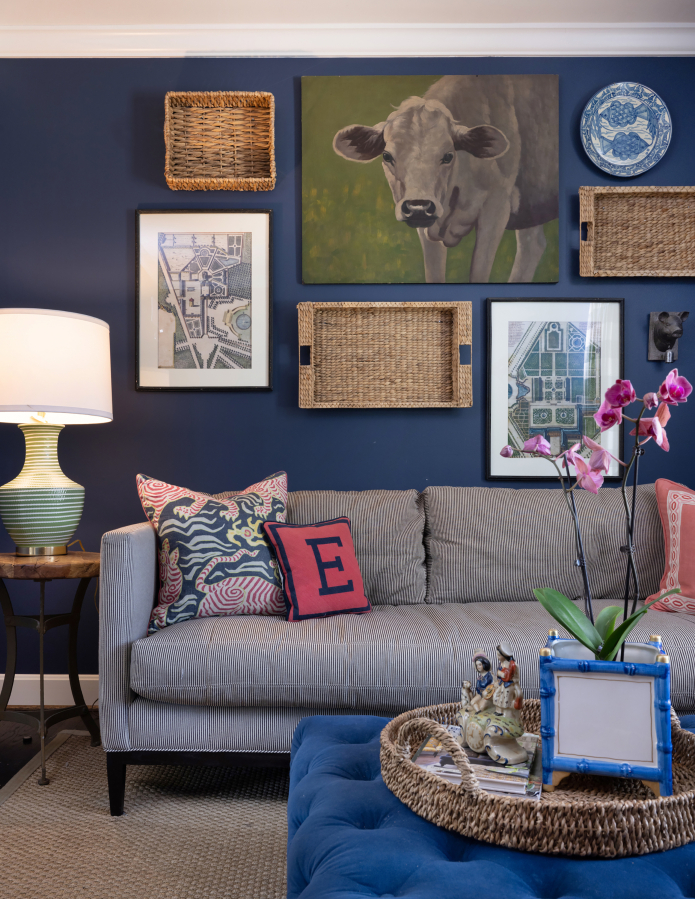 The sitting room's walls are dressed in a rich navy that complements the buttery velvet ottoman in the middle of the room and sets the tone for a bold and vibrant space that still brings an air of relaxation.