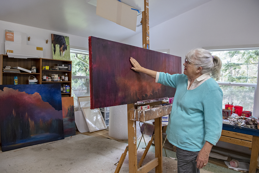 Retired landscape painter Ann Ruttan looks over a painting she made depicting an ember fire as seen at her home studio in early April. After driving through the Santiam Fire during the Labor Day holiday in 2020, Ruttan processed her trauma through painting. She is one of three artists featured in Art at the CAVE's June exhibit who use their work to inform others on the connection between climate change and wildfires. At top, the name of artist Ann Ruttan as seen at the bottom of one of her paintings.
