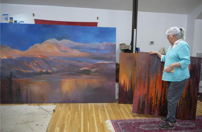 Retired landscape painter Ann Ruttan looks over paintings that depict the Eagle Creek Fire in her Portland home studio the morning of April 3.
