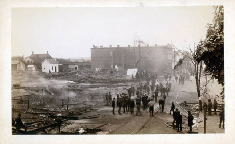 A firehose winds through a crowd of gawkers along Main Street at the edge of the Vancouver inferno of 1889. The firestorm gutted much of the city's downtown district, swallowing 26 buildings and damaging many more. After the torched real estate changed hands, the new owners rebuilt the four-block area in brick.