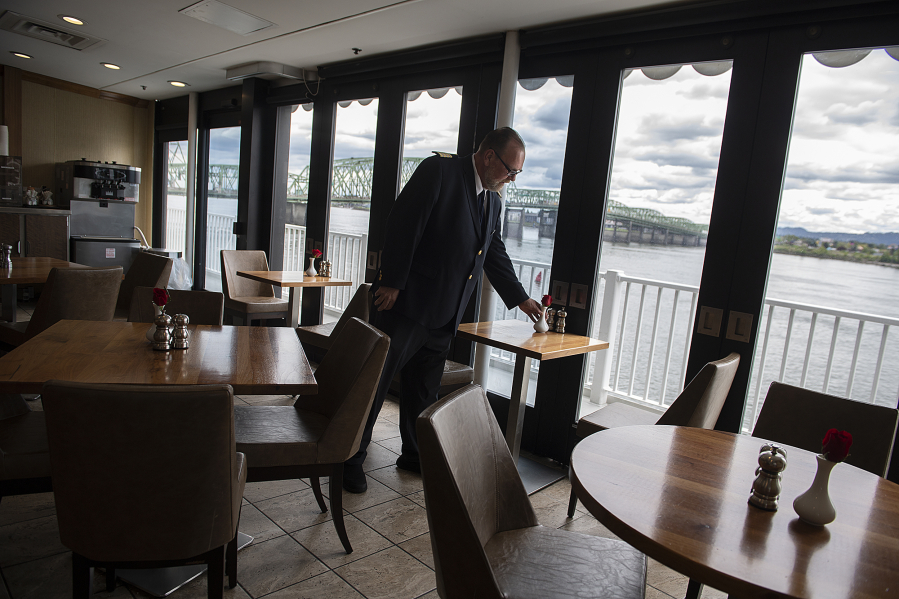 Large windows provide scenic views of the Columbia River for passengers aboard the American Empress as hotel director Terry Lunder prepares the casual dining room for the next meal Monday afternoon.