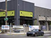 A motorist passes by the New Seasons under construction in Uptown Village on Wednesday morning, May 3, 2023.