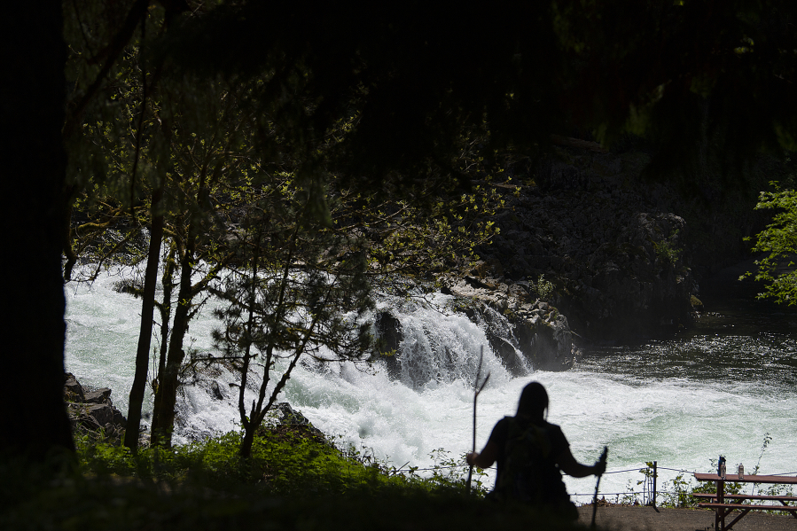 A hiker takes in a scenic view as springtime sunshine illuminates rushing water while it pours over the rocky cliffs of Lucia Falls. Forecasters predict the sunshine will stay around for the rest of the week with summerlike temperatures over the weekend.
