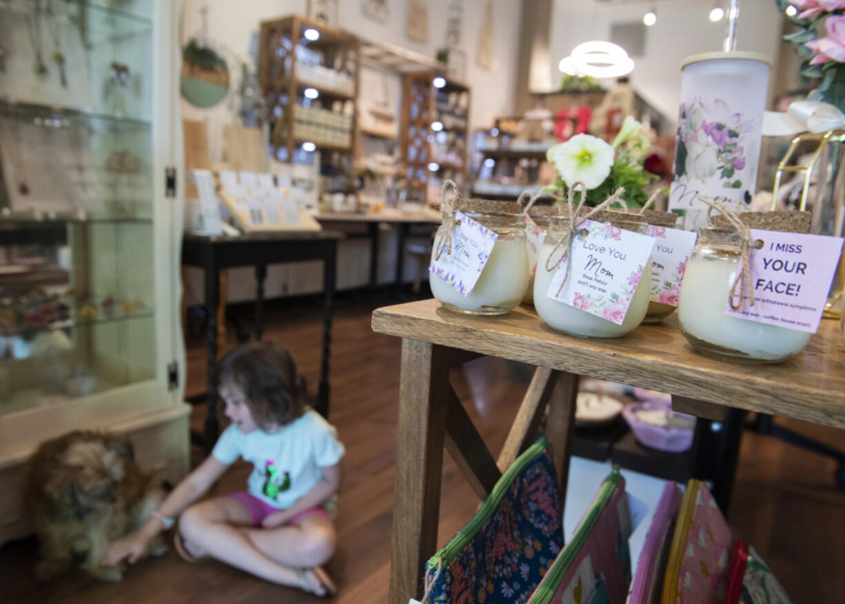 A selection of Mother's Day gift ideas are seen on display at Sweet Intention gift boutique as Camas resident Joelle Wilcox, 4, bonds with shop dog Daisy on Thursday afternoon. The holiday is a busy time for Clark County's retailers and restaurants.