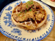Two fried tenders are served on an airy waffle with a side of housemade vanilla syrup at Cecilia in Vancouver.
