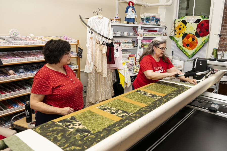 Margaret Murray and Miki Landis use a longarm sewing machine during a meeting of Fort Vancouver Quilts of Valor, the local chapter of a nationwide Quilts of Valor organization.