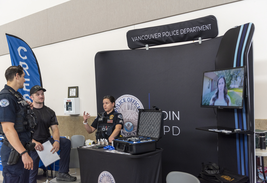 Vancouver Police Department Sgt. Danielle Wass, right, talks with officers Brandon Riedel, center, and Brandon Esau on Thursday at the Public Safety and First Responder Career Fair at Camp Withycombe in Clackamas, Ore.