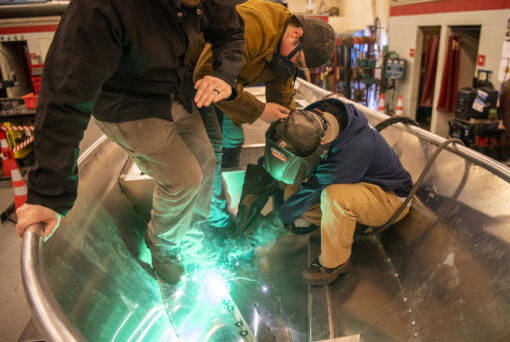 Clark College student Hallie Tibbit, right, welds a bar to the bottom of a metal boat as River Fortier, center, watches during an Advanced TIG (tungsten inert gas) welding class at Clark College. The boat, the students' final project, will be put to the test at Lacamas Lake in less than three weeks, a rite of passage for those graduating from the program, a symbolic send-off to their next adventure.