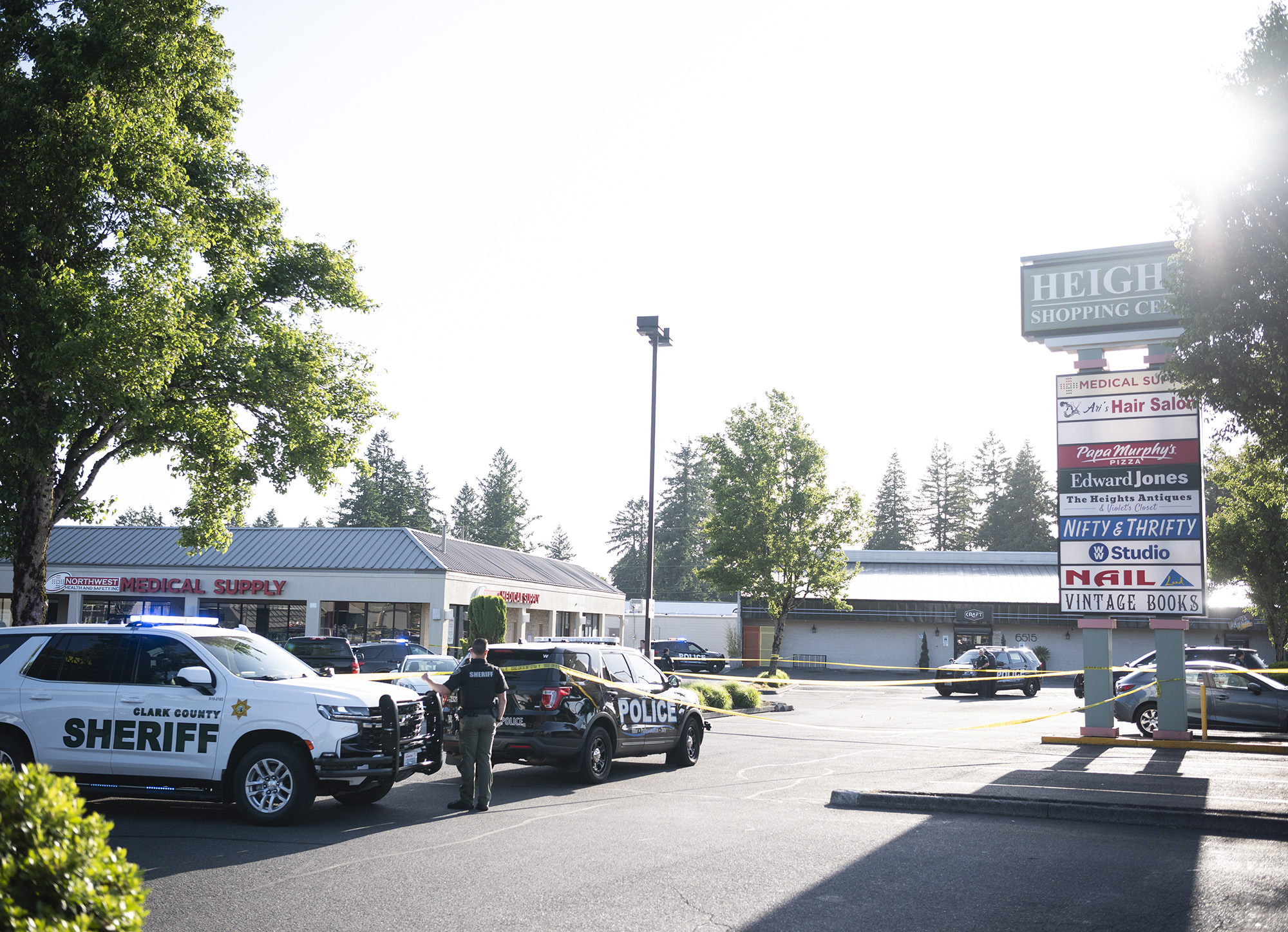 Clark County Sheriffs Office and Vancouver Police Department vehicles sit around police tape on Tuesday, May 30, 2023, at the site of a fatal shooting in the Heights Shopping Center parking lot.