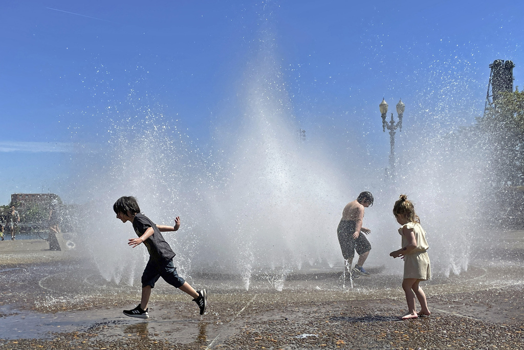 Children play in a fountain to cool off in downtown Portland, Ore., Friday, May 12, 2023. An early May heat wave this weekend could surpass daily records in parts of the Pacific Northwest and worsen wildfires already burning in western Canada, a historically temperate region that has grappled with scorching summer temperatures and unprecedented wildfires fueled by climate change in recent years.