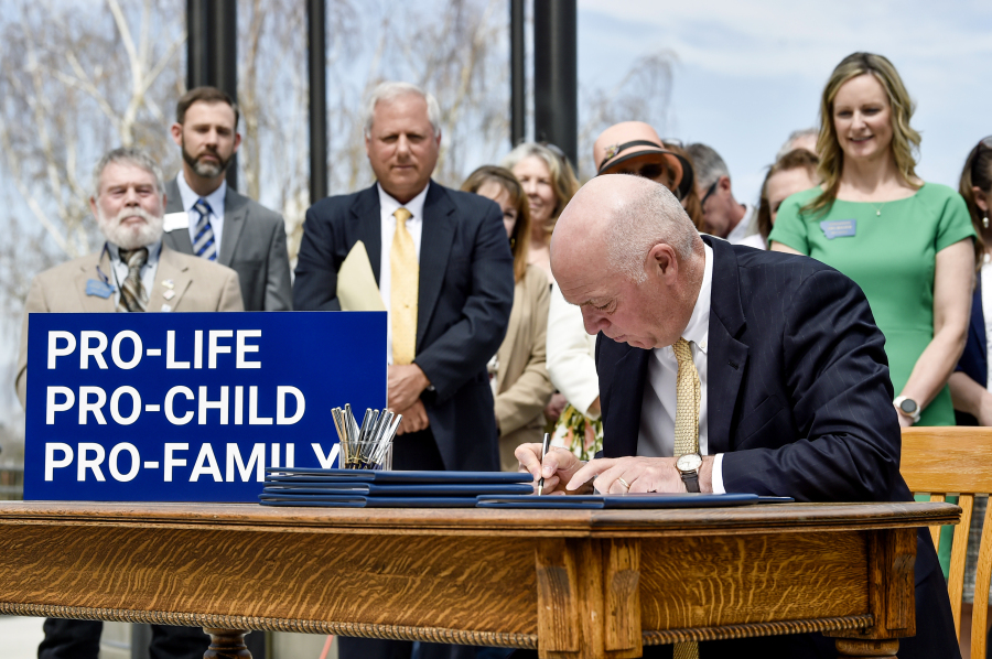 FILE - Gov. Greg Gianforte signs a suite of bills aimed at restricting access to abortion during a bill signing ceremony on the steps of the State Capitol, in Helena, Mont., on May 3, 2023. A judge on Thursday, May 18, 2023, granted Planned Parenthood of Montana's request to temporarily block enforcement of a law that bans the abortion method most commonly used after 15 weeks of pregnancy until he can hear arguments from both sides at a hearing on Tuesday, May 23.