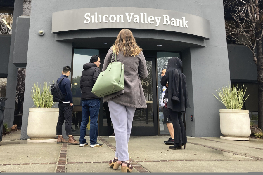 FILE - People stand outside a Silicon Valley Bank branch in Santa Clara, Calif., on March 10, 2023. The recent collapse of a trio of midsize banks, including Silicon Valley Bank, has once again raised questions on whether executive compensation is tilted toward short-term gains rather than companies' long-term health.