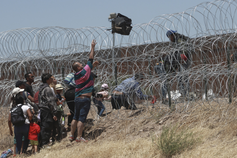FILE - Migrants cross a barbed-wire barrier at the US-Mexico border, as seen from Ciudad Juarez, Mexico, Thursday, May 11, 2023. Migrants rushed across the Mexico border in hopes of entering the U.S. in the final hours before pandemic-related asylum restrictions are lifted.