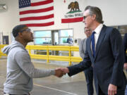 In this photo provided by the California Governor's Office, Governor Gavin Newsom, right, shakes hands with a MOXION employee Thursday, May 25, 2023, in Richmond, Calif. Newsom toured the battery manufacturing plant and touted his updated plan to ease the permitting process for new clean energy projects.