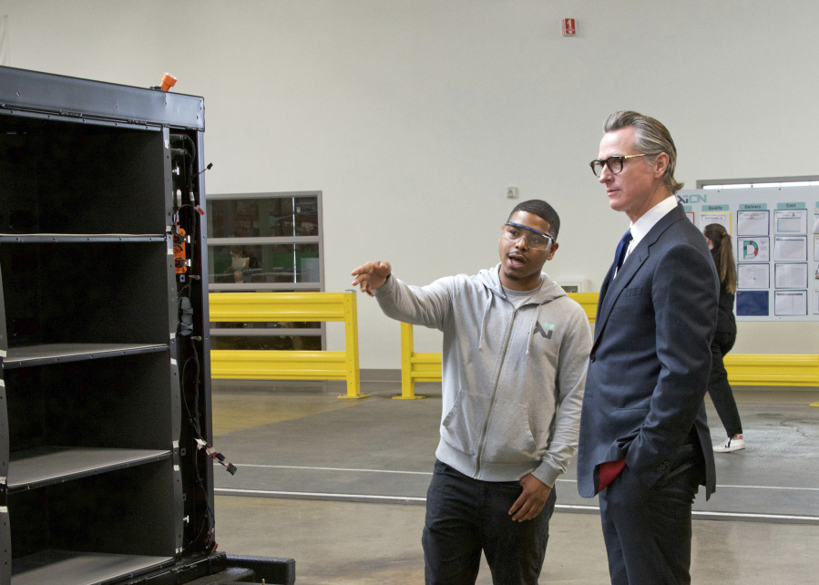 In this photo provided by the Governor's Office, Gov. Gavin Newsom, right, talks to a MOXION employee Thursday, May 25, 2023, in Richmond, Calif. Newsom toured the battery manufacturing plant and touted his updated plan to ease the permitting process for new clean energy projects.