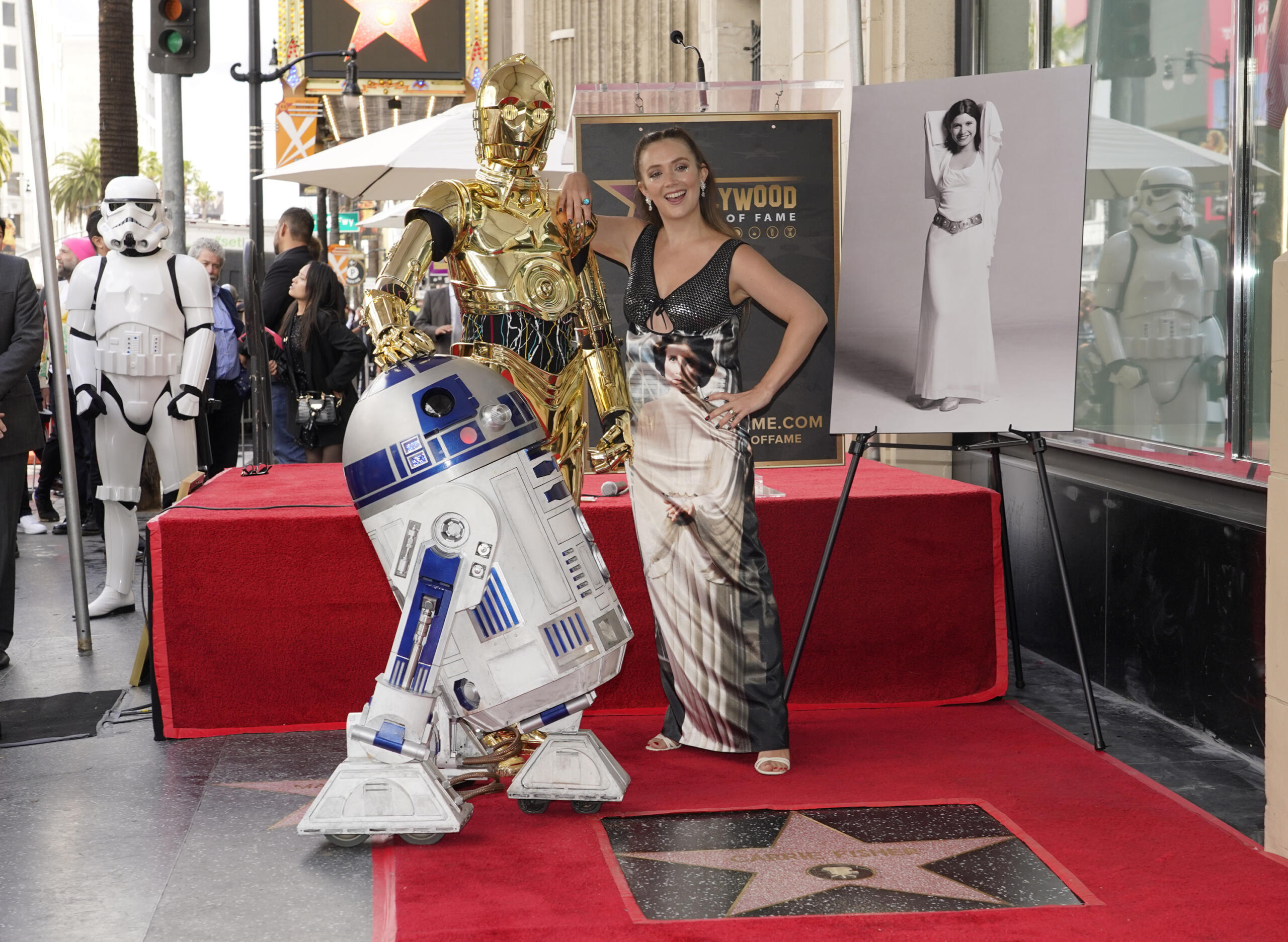 Billie Lourd, daughter of the late actress Carrie Fisher, pictured at right, poses with Fisher's star on the Hollywood Walk of Fame alongside "Star Wars" characters C-3PO and R2-D2, during a posthumous ceremony in Los Angeles on Thursday, May 4, 2023. The day is also known as May the Fourth in tribute to the "Star Wars" films in which Fisher played Princess Leia.