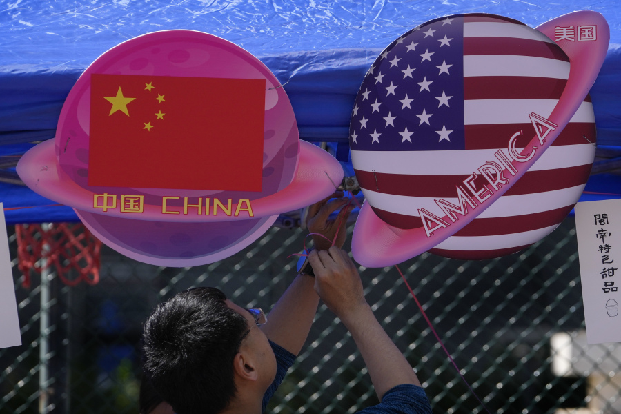 A vendor sets up foods and beverages at a booth displaying planets shaped of China and American flags during a Spring Carnival in Beijing on May 13, 2023. Hong Kong's leader on Tuesday, May 16 said the sentencing on spying charges of a U.S.