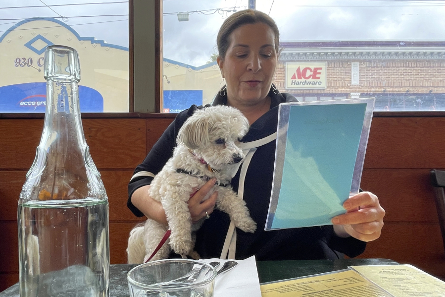 Ilana Minkoff checks out the menu with her dog JoJo Wigglebutt at a restaurant in San Francisco on Friday, May 5, 2023. Just in time for the summer dining season, the U.S. government has given its blessing to restaurants that want to allow pet dogs in their outdoor spaces.