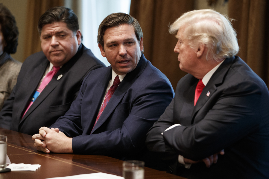 FILE - Gov.-elect Ron DeSantis, R-Fla., talks with President Donald Trump during a meeting with newly elected governors in the Cabinet Room of the White House, Dec. 13, 2018, in Washington. From left, Governor-elect J.B. Pritzker, D-Ill., DeSantis, and Trump.