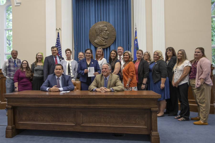 Nevada Governor Joe Lombardo (right sitting) with Nevada Secretary of State Cisco Aguilar pose with state election officials after signing an election worker protection bill into law as Secretary of State Cisco Aguilar looks on at the old Assembly Chambers in Carson City, Nev., Tuesday, May 30, 2023. (AP Photo/Tom R.