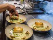 FILE - A worker arranges food onto plates in the kitchen of a restaurant in New York on Dec. 14, 2021. Food workers who showed up while sick or contagious were linked to about 40% of restaurant food poisoning outbreaks with a known cause between 2017 and 2019, federal health officials said Tuesday, May 30, 2023.