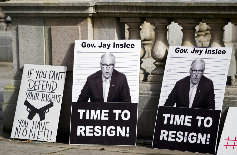 Signs left by protesters call on Washington Gov. Jay Inslee to resign, ahead of his signing of multiple gun violence prevention bills, Tuesday, April 25, 2023, at the Capitol in Olympia, Wash.
