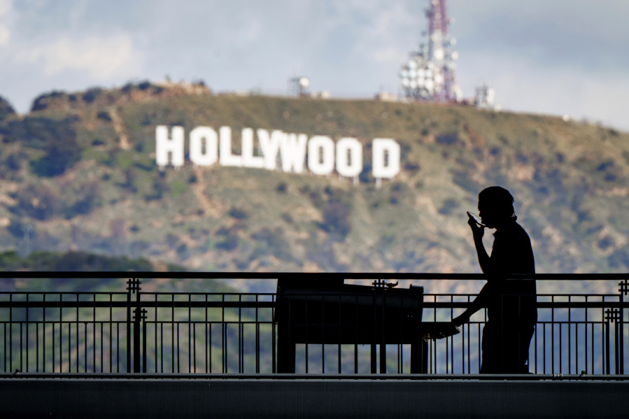 FILE - A worker wheels equipment past the famous Hollywood sign as preparations continue on March 8, 2023, for the 95th Academy Awards at the Dolby Theatre in Los Angeles. Television and movie writers declared late Monday, May 1, that they will launch an industrywide strike for the first time in 15 years, as Hollywood girded for a walkout with potentially widespread ramifications in a fight over fair pay in the streaming era.  (AP Photo/J.