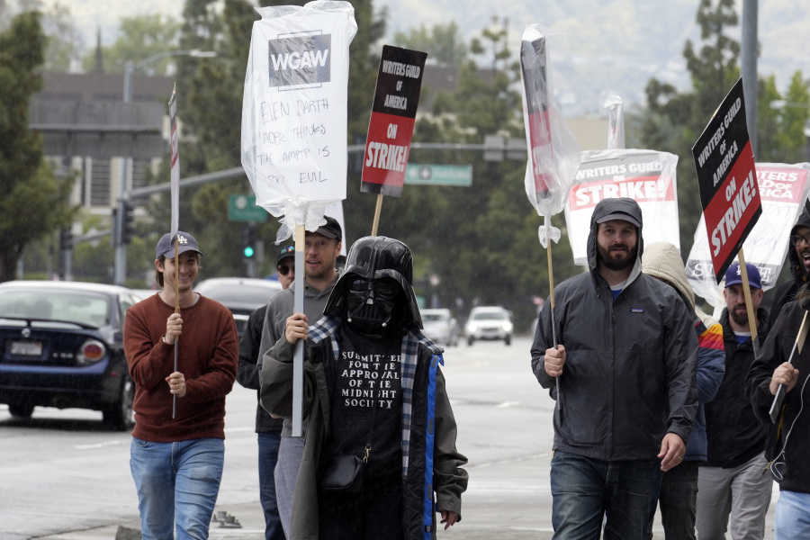 Writer Montserrat Luna-Ballantyne, front center, wears a Darth Vader mask while picketing with fellow members of The Writers Guild of America outside of Universal Studios Thursday, May 4, 2023, in Universal City, Calif. The first Hollywood strike in 15 years commenced Tuesday as the 11,500 members of the Writers Guild of America stopped working when their contract expired.