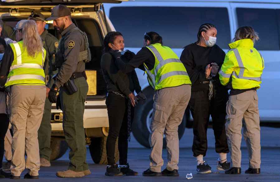 Shackled migrants are inspected by U.S. Immigration and Customs Enforcement agents while boarding a repatriation flight to Guatemala in El Paso, Texas, Wednesday, May 10, 2023. President Joe Biden's administration on Thursday will begin denying asylum to migrants who show up at the U.S.-Mexico border without first applying online or seeking protection in a country they passed through, according to a new rule released Wednesday, as U.S. officials warned of difficult days ahead as a key limit on immigration is set to expire.