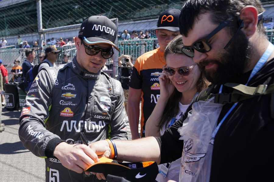 Fan-favorite Pato O'Ward signs an autograph during a recent Indianapolis 500 practice session. His jersey sales are tops in IndyCar, nearly 35% higher than the next driver. His collective merchandise offerings supply draws the highest revenue of any driver retail line.