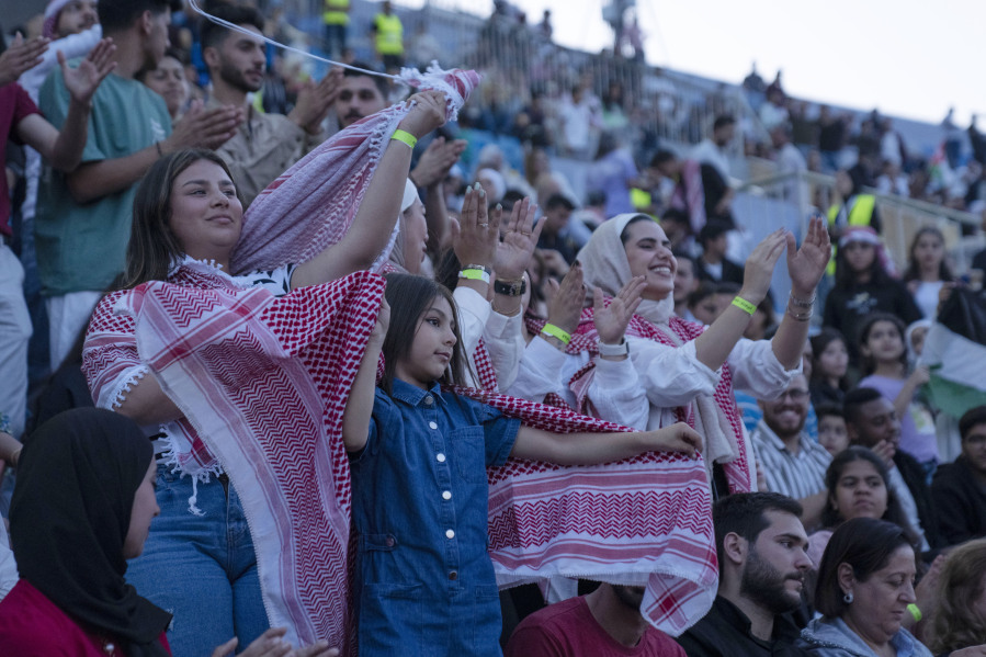 Jordanian women wearing the traditional Jordanian red and white checkered scarf and T-shirts dance and sing during a concert at a sports stadium in Amman, Jordan, Monday, May 29, 2023. The free concert featuring well-known Arab singers, including Egyptian star Tamer Hosny, was part the celebrations leading up to the wedding of Crown Prince Hussein and his fiancee, Saudi architect Rajwa Alseif later this week.