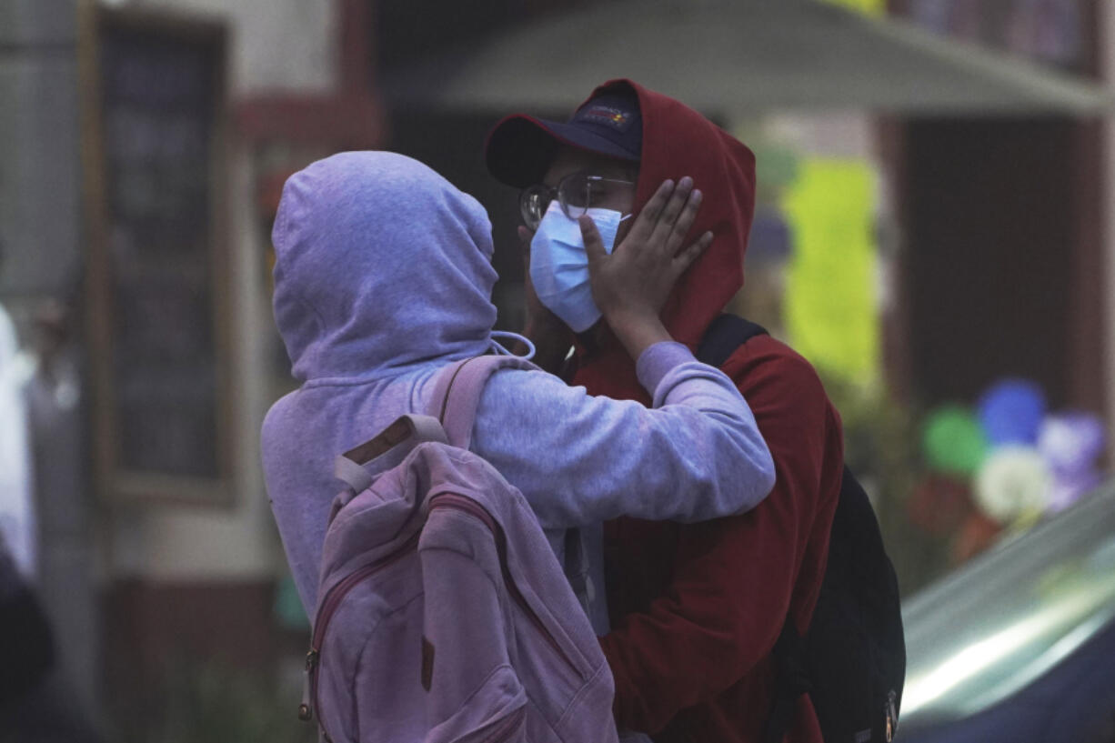 A couple wearing hoodies and masks to protect themselves from the ash fall of the Popocat?petl volcano embraces in Atlixco, Mexico, Monday, May 22, 2023. The volcano's activity has increased over the past week. Evacuations have not been ordered, but authorities are preparing for that scenario and telling people to stay out of 7.5-mile (12-kilometer) radius around the peak.