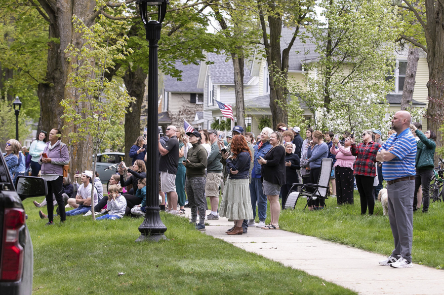 Onlookers watch as representatives from the Michigan Department of Natural Resources, DNR Conservation Officers, Traverse City Mich, Police, Traverse City Fire and Traverse City Light and Power work to remove a black bear from a tree outside a Fifth Street home on Sunday, May 14, 2023 morning in Traverse City's Central Neighborhood.
