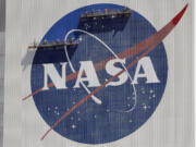 FILE - Workers on scaffolding repaint the NASA logo near the top of the Vehicle Assembly Building at the Kennedy Space Center in Cape Canaveral, Fla., May 20, 2020.