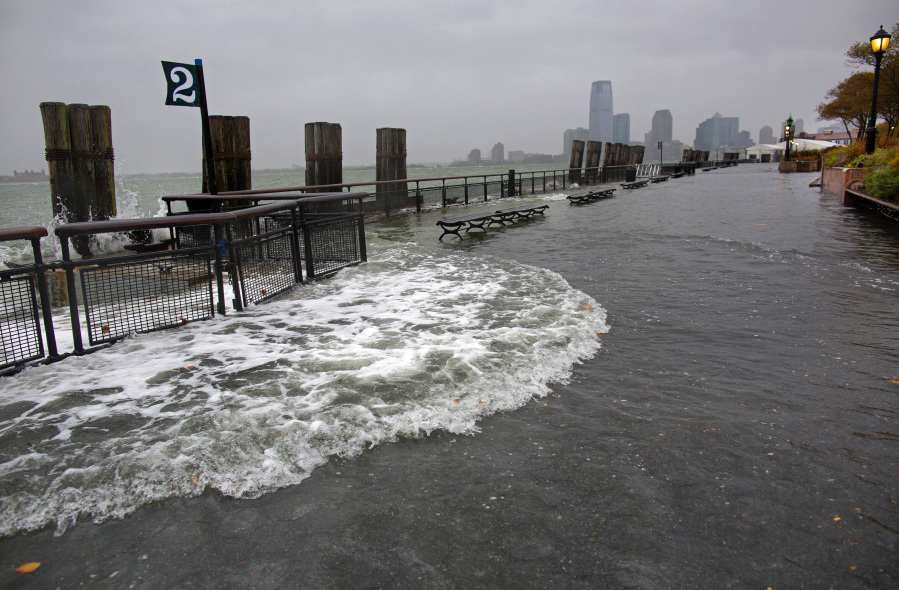 FILE -- Waves wash over the seawall near high tide at Battery Park in New York, Oct. 29, 2012, as Hurricane Sandy approaches the East Coast. If rising oceans aren't worry enough, add this to the risks New York City faces: The metropolis is sinking under the weight of its skyscrapers, apartment buildings, asphalt and humanity itself -- and will eventually become flooded by the Hudson River and Atlantic Ocean.