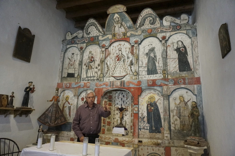 Master santero Felix Lopez, an artist trained in New Mexico's centuries-old tradition of religious sculpture and painting, speaks April 16 in front of the 1810s "reredo" or altarpiece he cleaned and preserved in the Holy Rosary Mission Church in Truchas, N.M.
