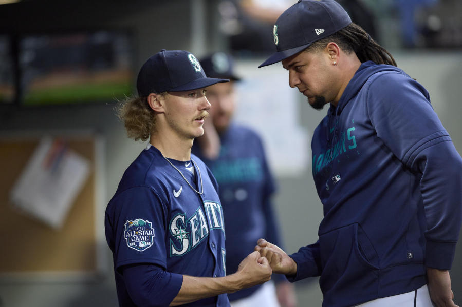 Seattle Mariners starting pitcher Bryce Miller, left, is greeted by pitcher Luis Castillo in the dugout after pitching sixth innings against the Oakland Athletics in a baseball game Wednesday, May 24, 2023, in Seattle.