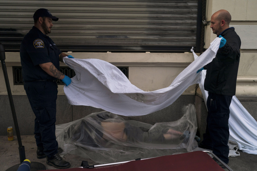 FILE - Forensic assistant Laurentiu Bigu, left, and investigator Ryan Parraz from the Los Angeles County coroner's office cover the body of a homeless man found dead on a sidewalk in Los Angeles on April 18, 2022. The 60-year-old man died from the effects of methamphetamine, according to his autopsy report. Drug overdose deaths in the U.S. went up slightly in 2022 after two big leaps during the pandemic. (AP Photo/Jae C.