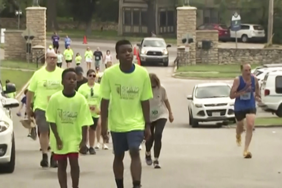 In this image made from video provided by KCTV, Ralph Yarl, center, wearing a bright green "Team Ralph" shirt, participates in a walk in an event called "Going the Distance for Brain Injury" at Loose Park in Kansas City, Mo., Monday, May 29, 2023. Yarl, a Black teenager who was shot in the head and arm in April after mistakenly ringing the wrong doorbell, walked at the brain injury awareness event Monday in his first major public appearance since the shooting.