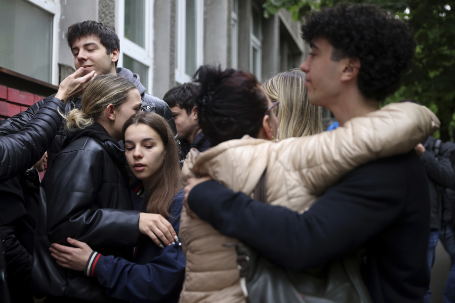 People mourn the victims near Vladislav Ribnikar school in Belgrade, Serbia, Thursday, May 4, 2023. Police say a 13-year-old who opened fire at his school drew sketches of classrooms and made a list of people he intended to target. He killed multiple fellow students and a school guard before being arrested.